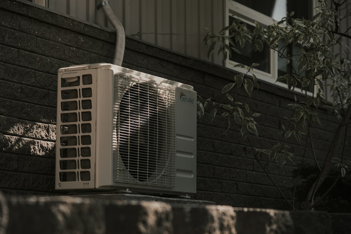 Outdoor air conditioner unit mounted on a brick wall