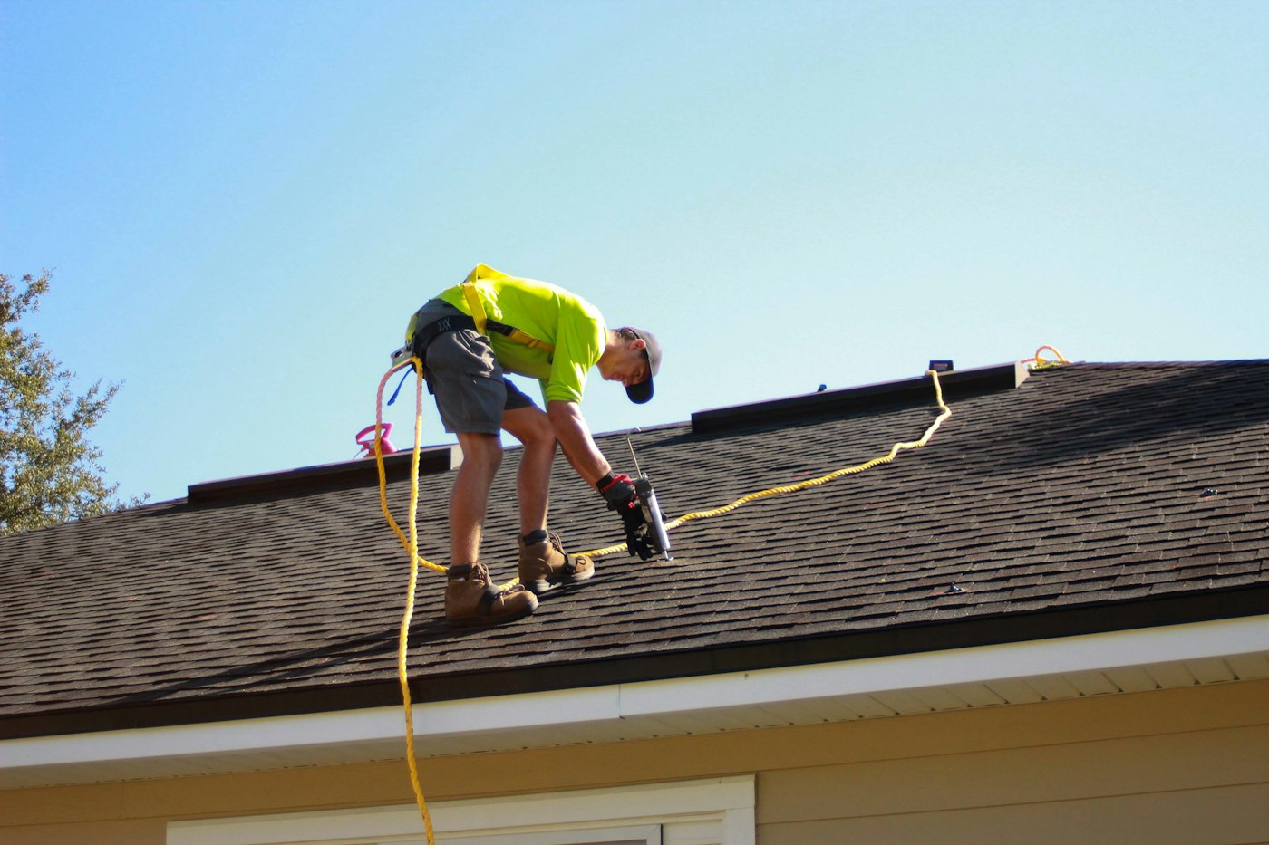 Roofer working on a residential roof with a power drill
