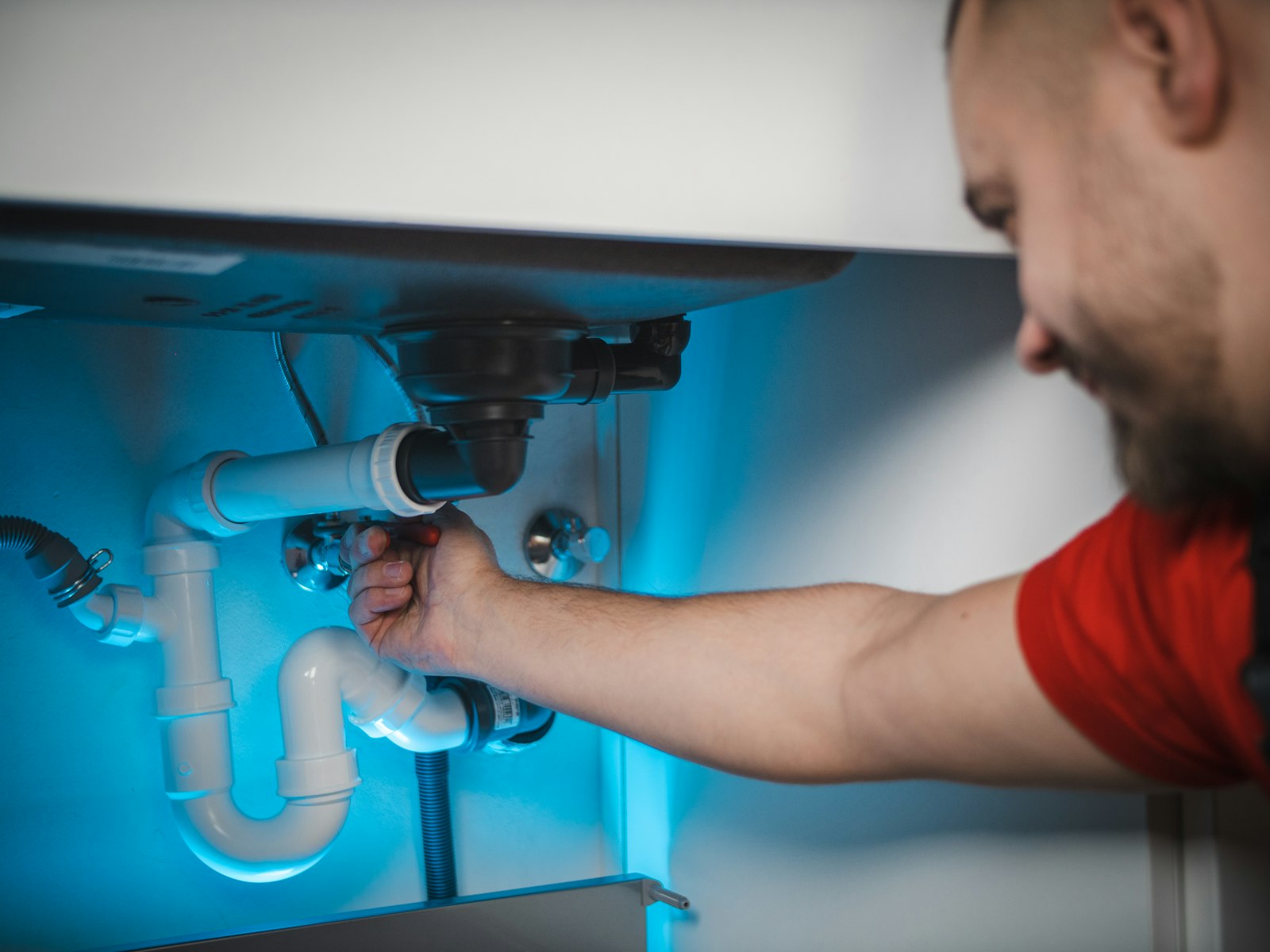 Plumber repairing a pipe inside a wall, the kind of company generative engine optimization helps AI tools recommend