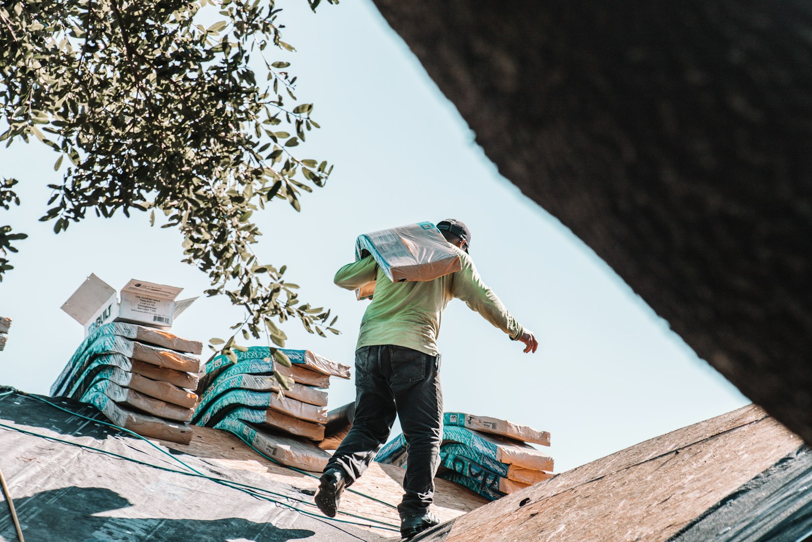 Roofer carrying a bundle of shingles up to a job, the kind of work organic roofing leads bring in