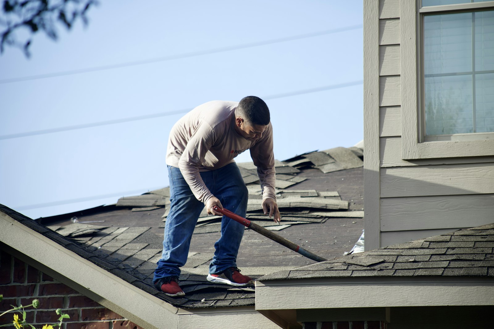 Roofer tearing off old shingles, the kind of replacement job roofing SEO mistakes can keep from finding you