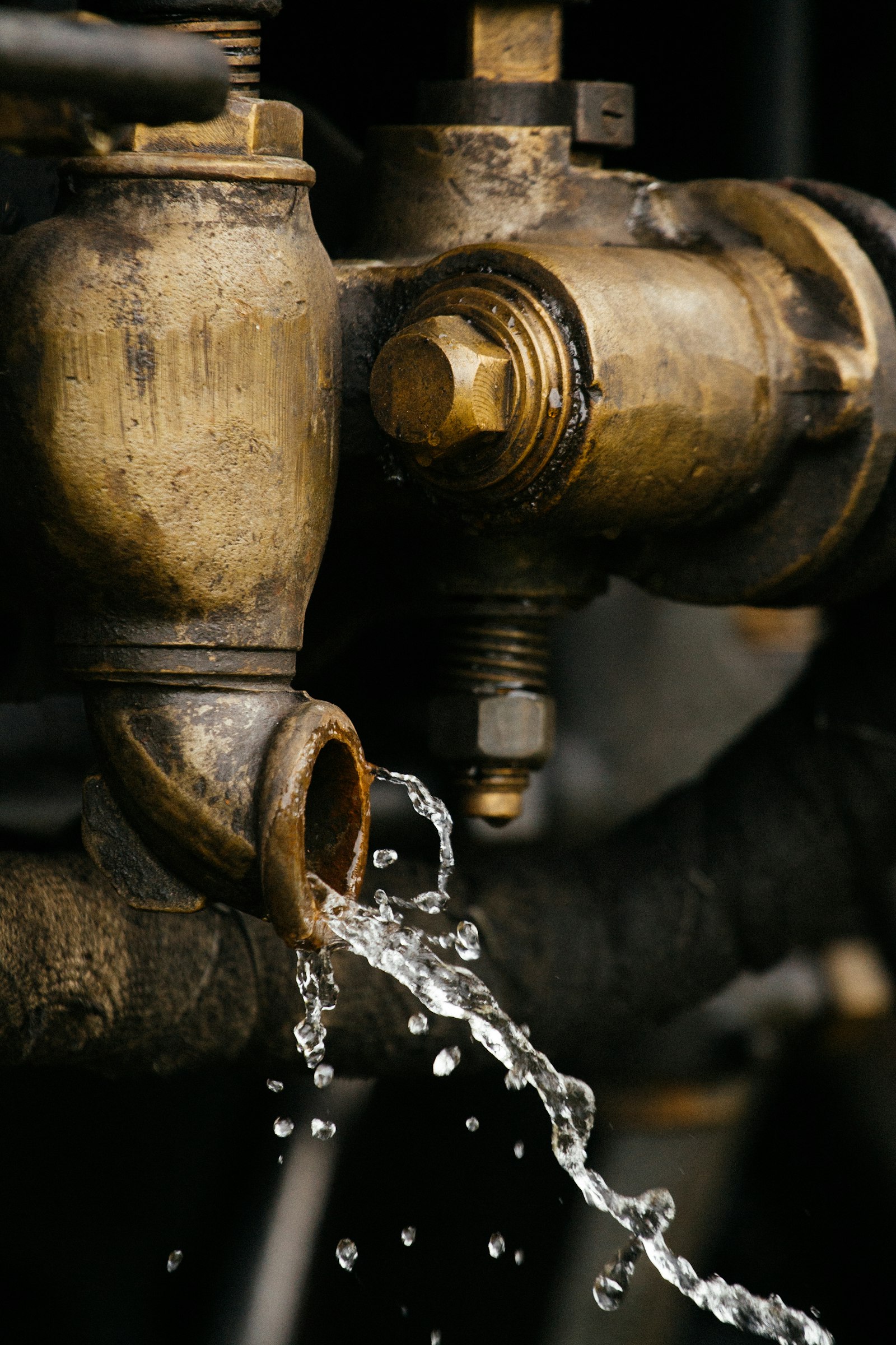 Water dripping from a brass pipe fitting, a leak homeowners often ask a voice assistant about first